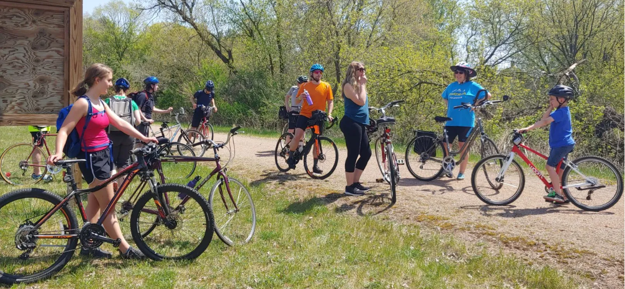 A group of people taking a break while riding their bikes on a dirt path